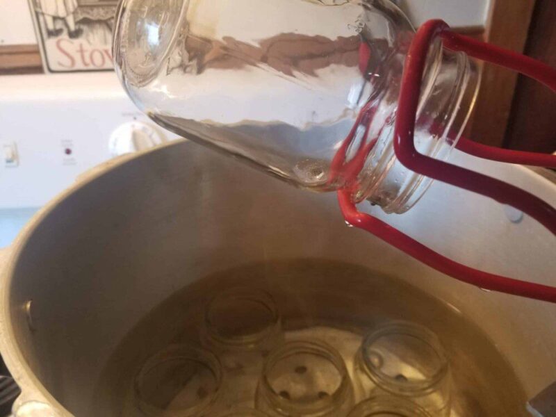 Image of canning jar being tipped sideways to remove water.